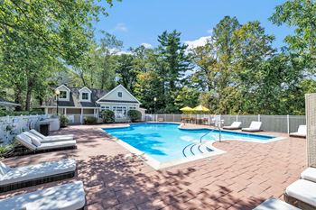 A pool surrounded by trees and a house in the background.